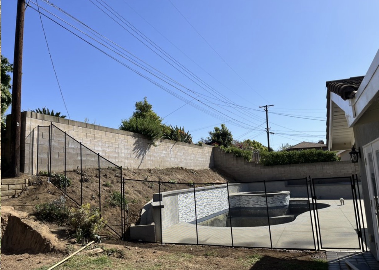 Hillside pool with tall mesh safety fence