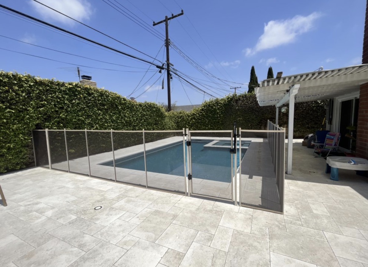 Travertine patio pool with tan mesh fence