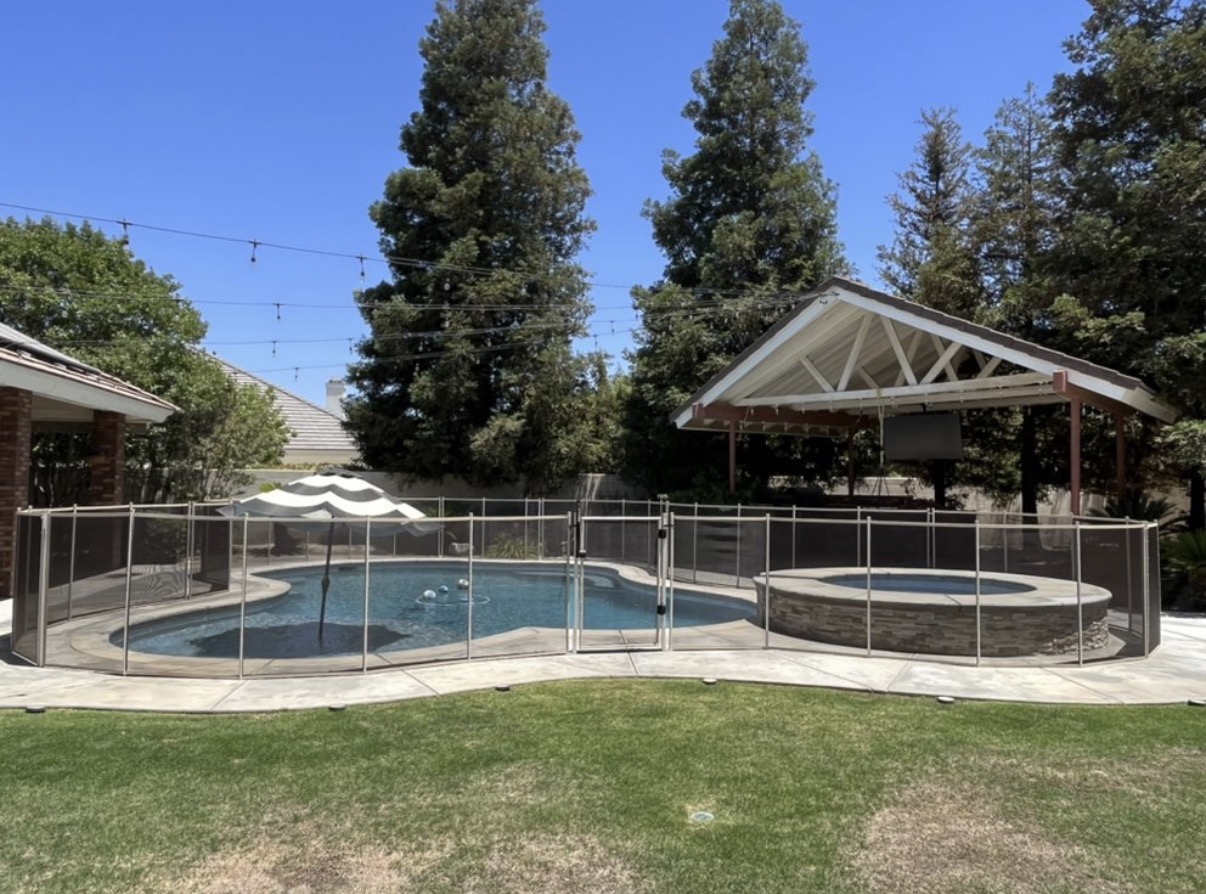 Pool and spa with brown mesh fence and umbrella