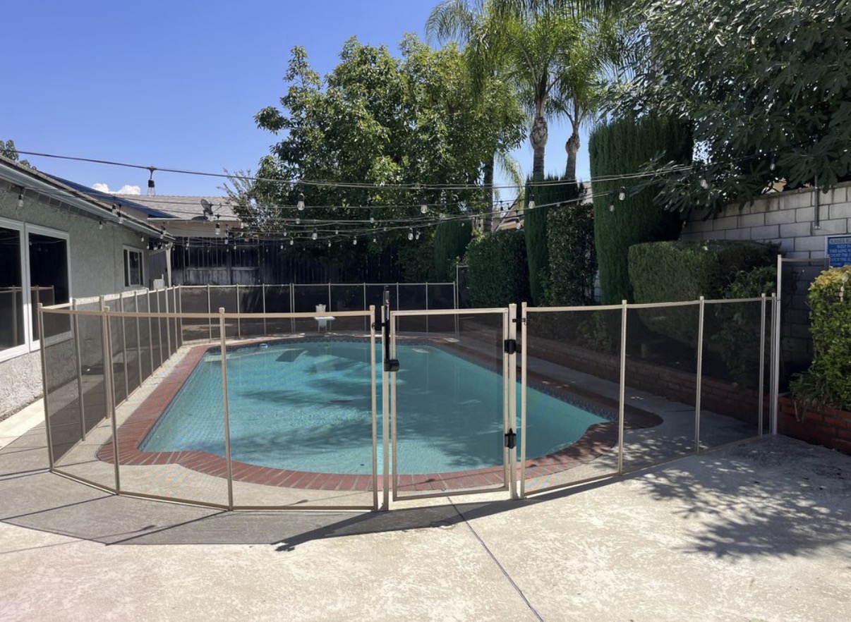Backyard pool with tan removable safety fence