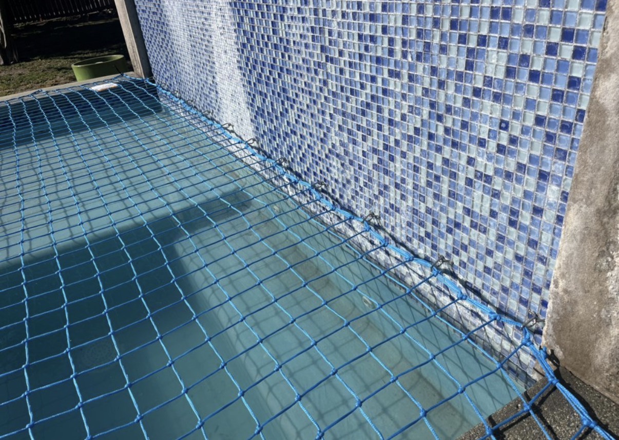 Blue pool safety net along mosaic tile wall