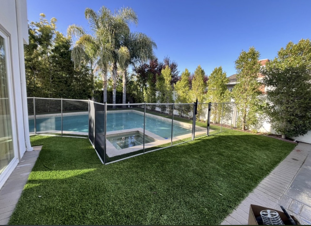 Modern pool and spa with clear safety fence on turf