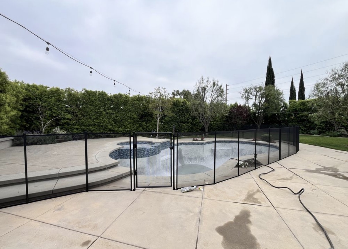 Curved pool with black safety fence and gate